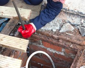 Professional drain technician using a high-pressure water jet machine to clear a residential drain line